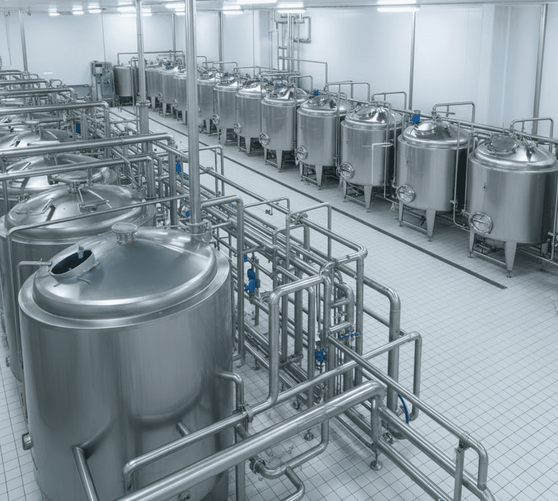 Industrial dairy processing facility with stainless steel tanks and CIP piping systems